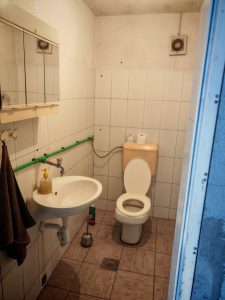 kupaonica-prije-renovacije-pločice-wc Pogled na staru kupaonicu s pločicama i WC školjkom prije renovacije mikrocementom
