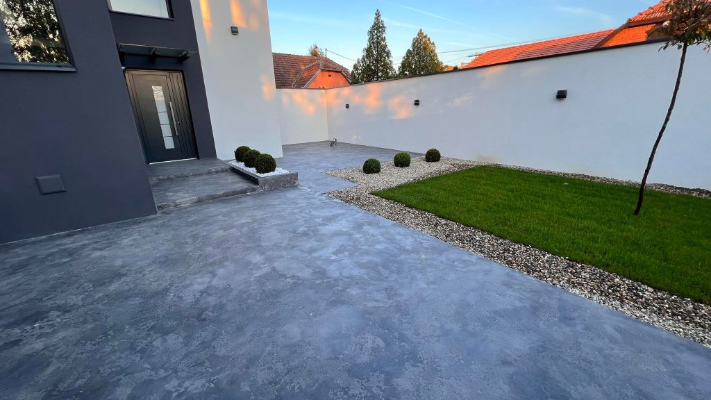 Moderna okućnica s mikrocement podom, zelenim travnjakom i dekorativnim šljunkom