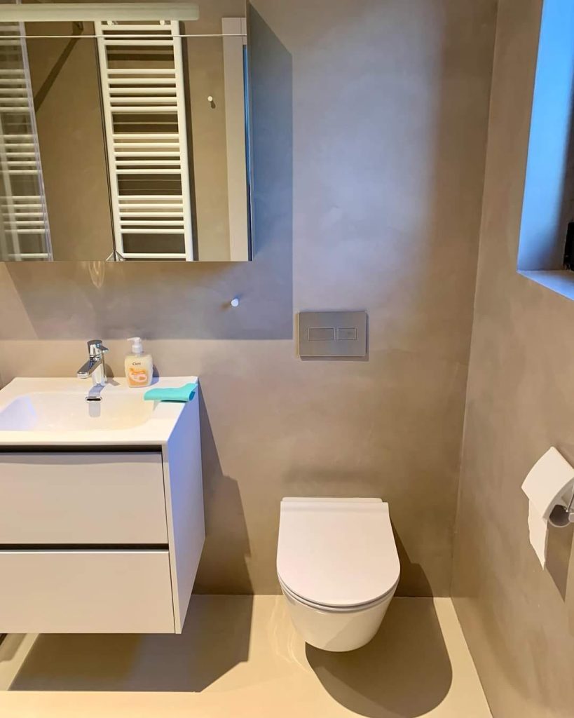 Svijetla kupaonica s mikrocement zidovima, WC školjkom i ormarićem